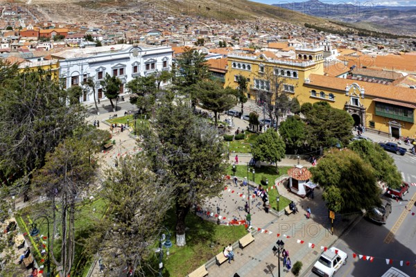 Square in a city with surrounding buildings and trees, lively with people, view over the city of Potosi in Bolivia
