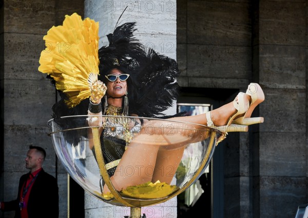 An erotic model sits in an oversized champagne glass at the Grand Opening of the Venus Erotic Fair in Berlin