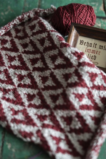 Knitted piece with ball of wool and framed picture with the lettering Behalt ich immer lieb