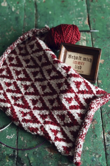 Knitted piece with ball of wool and framed picture with the lettering Behalt ich immer lieb