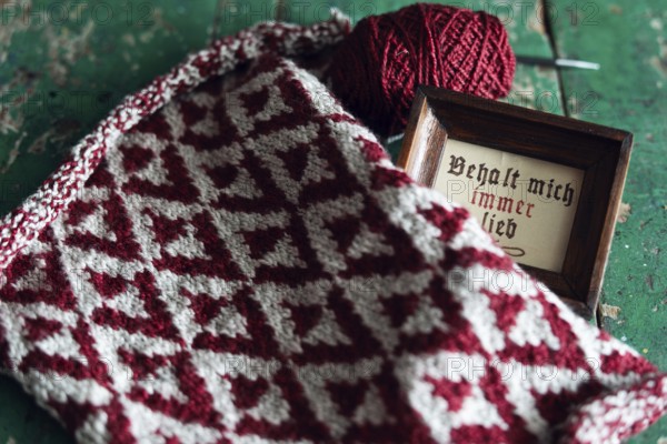 Knitted piece with ball of wool and framed picture with the lettering Behalt ich immer lieb