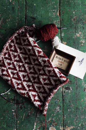 Knitted piece with ball of wool and framed picture with the lettering Behalt ich immer lieb