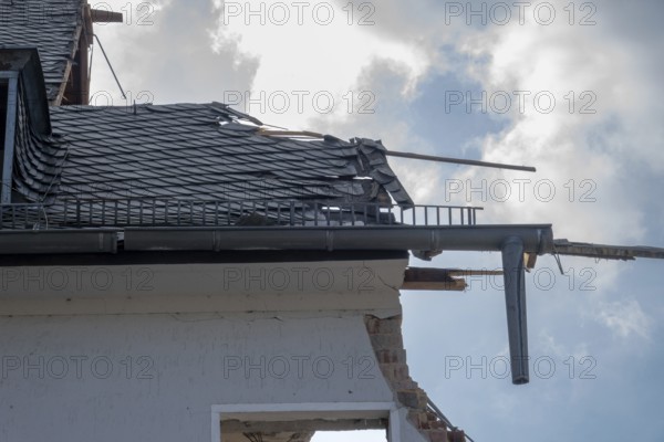 House roof with broken slate tiles and exposed framework showing destruction