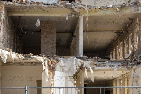 Partially demolished building showing exposed interior structure, rubble, and debris