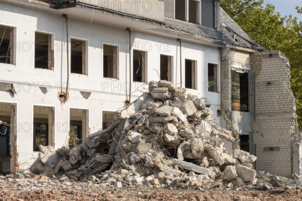 Concrete and brick rubble piling up in front of a partially demolished building
