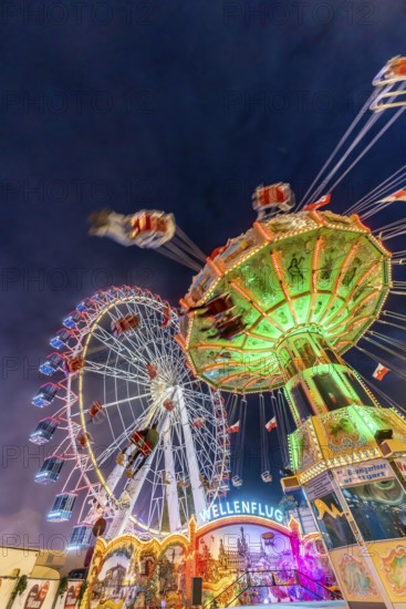 Folk festival time in Stuttgart. Ferris wheel and chain carousel in the evening. The 178th Cannstatter Volksfest on the Wasen is one of the most important traditional festivals in Germany. In addition to the large festival tents, the Wasen is characterised by fairground attractions. Around 320 showmen, festival hosts and market traders expect around four million visitors. Bad Cannstatt, Stuttgart, Baden-Württemberg, Germany