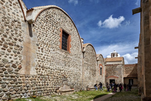 Historic stone buildings with curved roofs under a blue sky, people grouped outside, The historical museum of Potosi in Bolivia