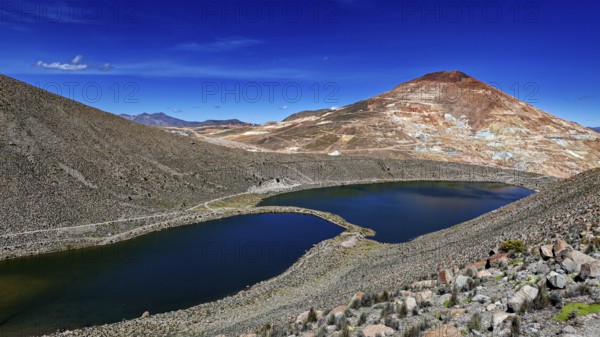 Volcanic mountain reflected in the lake, surrounded by barren landscape and under a bright blue sky, the silver mountain Cerro Rico near Potosi Bolivia