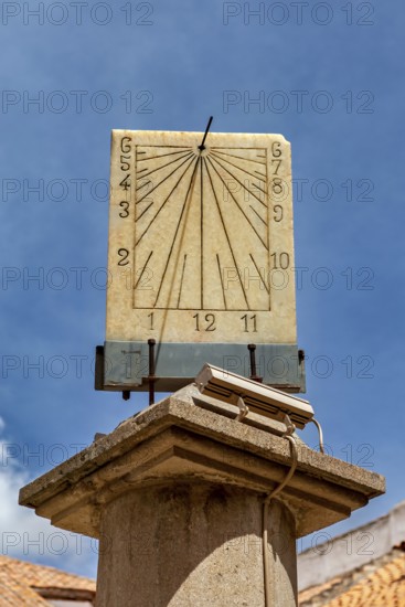Stone sundial, mounted on a column, with dial and hands in front of a bright sky, The sundial of Potosi in Bolivia