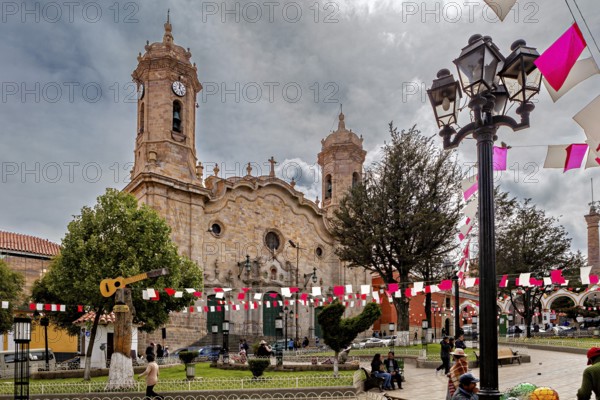 Lively square in front of a church with festive decorations and people, historic towers in the background, The churches in Potosi in Bolivia