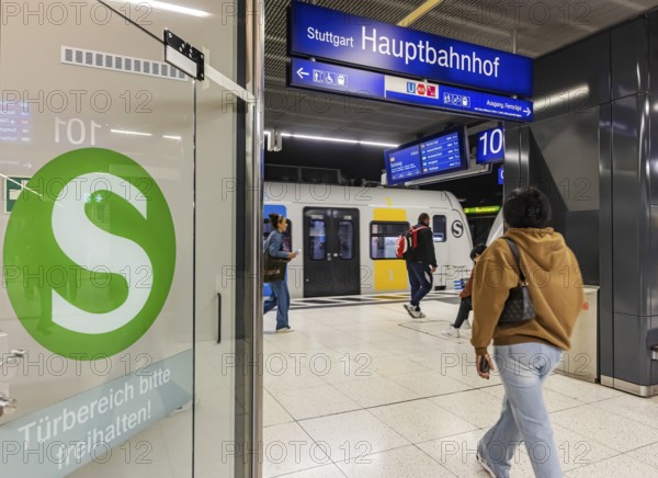 S-Bahn arriving underground at the main station stop. Platform with travellers and logo. Stuttgart, Baden-Württemberg, Germany