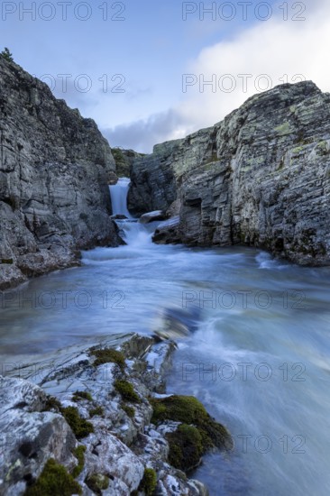 A river flows through a narrow gorge, over a small waterfall, surrounded by steep cliffs, Peer Gynt hytta, Rondane National Park, Otta, Innlandet, Norway