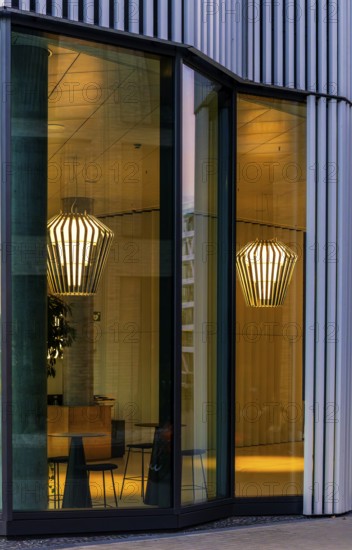 The picture shows the interior of a modern Berlin restaurant, taken in the evening, the scene is characterised by modern lighting fixtures reminiscent of large, glowing light bulbs, Berlin, Germany