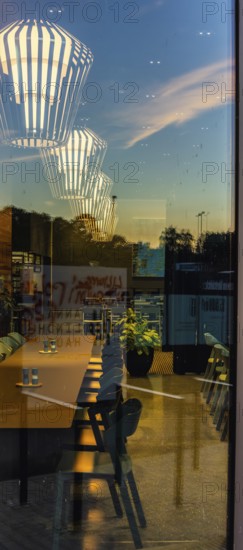 The picture shows the interior of a modern Berlin pub, taken in the evening. The scene is characterised by modern lighting fixtures reminiscent of large, glowing light bulbs, Berlin, Germany