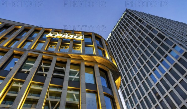 The picture shows modern office and commercial buildings at the central station, KPMG and Total Energie logo on the facade, warm evening light, frog perspective, Berlin, Germany