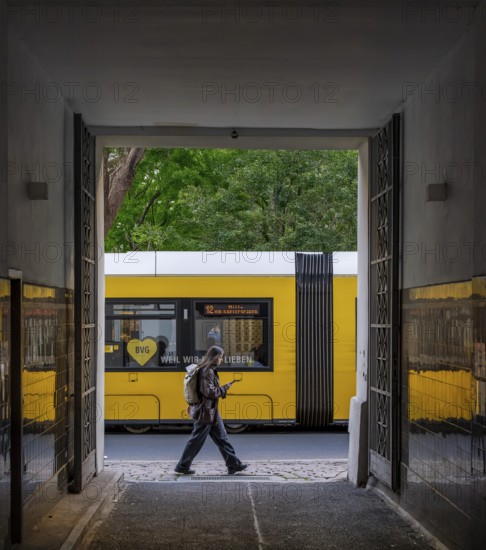 Urban environment in Berlin, a yellow tram can be seen through an open doorway. The scene captures a moment in the city's public transport system, Berlin, Germany