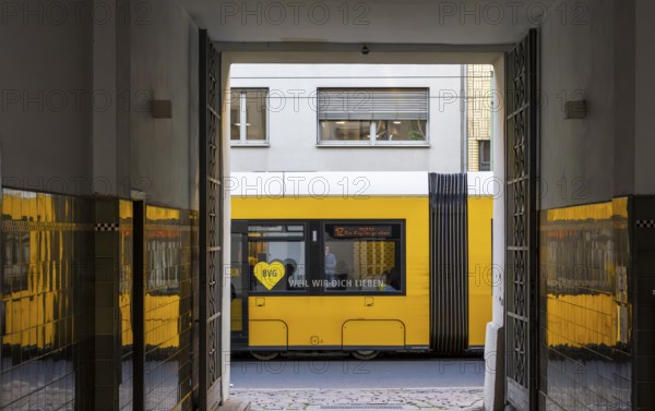 Urban environment in Berlin, a yellow tram can be seen through an open doorway. The scene captures a moment in the city's public transport system, Berlin, Germany