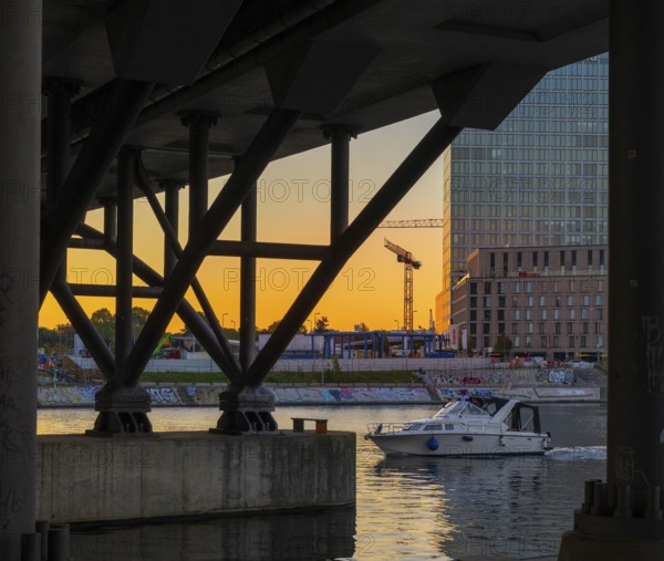 A view of the Berlin waterfront promenade at Humboldt harbour at sunset with modern architecture and construction cranes, Berlin, Germany