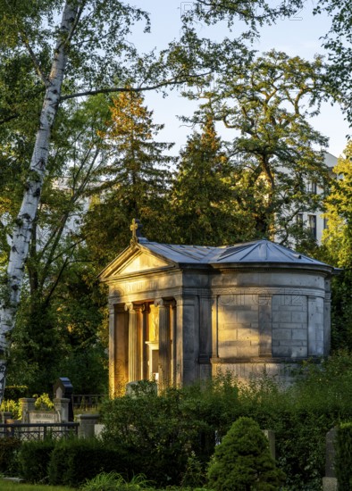 A small, classical mausoleum in the churchyard of Dorotheenstraße and Friedrichswerdersche Gemeinde, illuminated by sunlight, surrounded by trees and greenery, Berlin, Germany