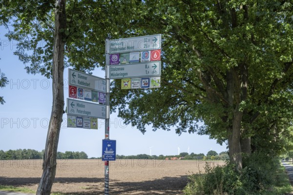 Signpost in front of a rural backdrop with fields and trees under a blue sky, Weser cycle path, Diethe, Stolzenau, Lower Saxony, Germany