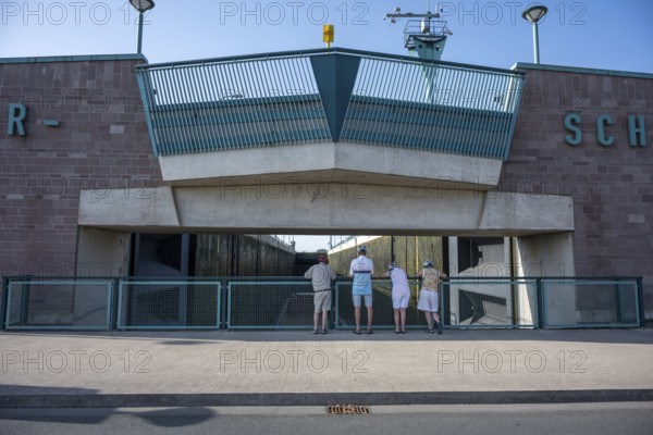 Four people stand in front of a modern lock structure made of concrete and blue railings, Minden waterway junction, Minden-Lübbecke, North Rhine-Westphalia
