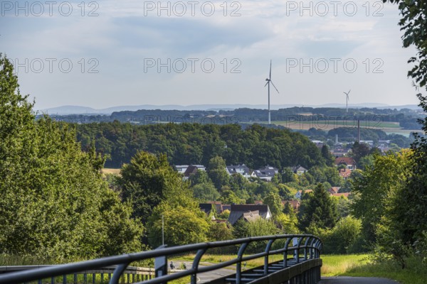 View of a village with wind turbines, surrounded by trees and fields, with a bridge in the foreground, Halle, Werther, Westphalia