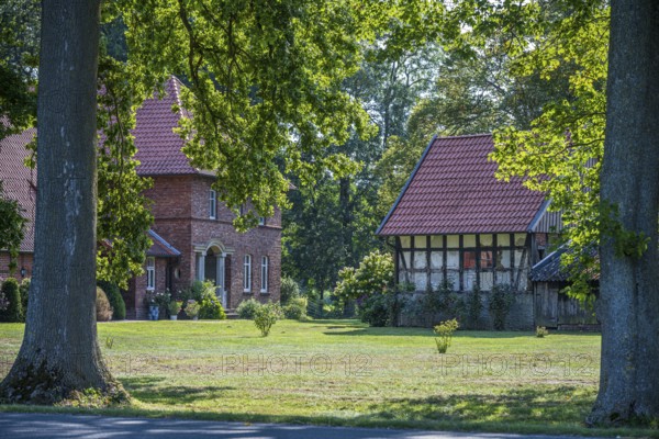 A large tiled roof house next to an older half-timbered building in a green landscape, Gütersloh, Westphalia