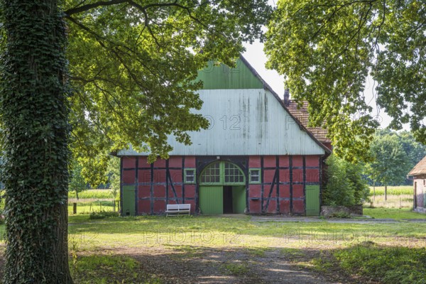A rustic half-timbered barn with open Tor tor, surrounded by trees and nature, Gütersloh, Westphalia