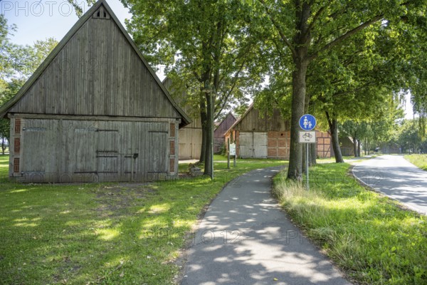 Half-timbered houses next to a cycle path surrounded by green meadows and trees, Weser cycle path, Scheunenviertel Schlüsselburg, Petershagen, North Rhine-Westphalia
