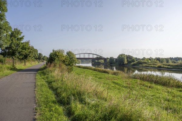 An idyllic river with a bridge surrounded by a green landscape under a clear sky, Weser, Weser cycle path, Minden-Lübbecke, North Rhine-Westphalia