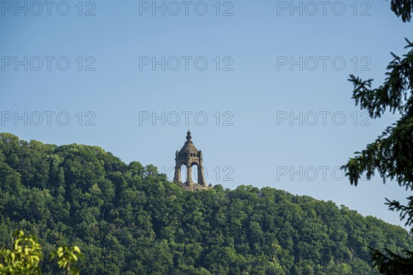 A monument rises on a wooded hill under a clear blue sky, Kaiser Wilhelm Monument, Porta-Westfalica, North Rhine-Westphalia