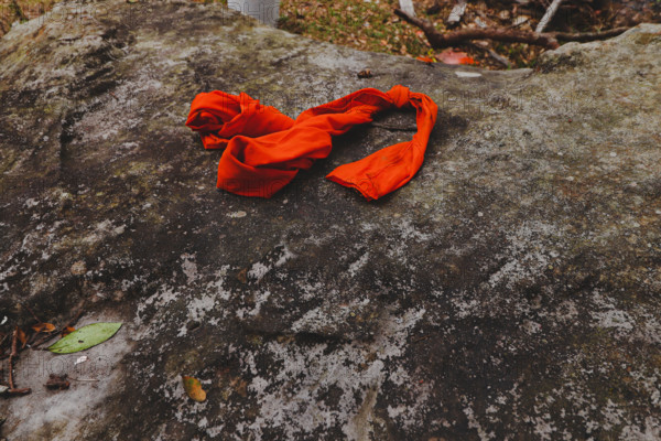 Bright orange cloth resting on a textured rock surface in a natural setting, Thailand