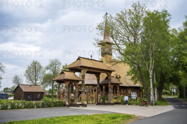 Wooden church with characteristic carvings, along a country road, surrounded by trees and sheds, The Romanian Orthodox church near Sögel in Emsland