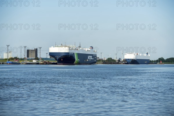 Two large cargo ships moored in the harbour, surrounded by water and blue sky, car freighters in the port of Emden