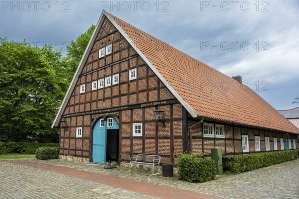 Traditional half-timbered house with red tiled roof and green surroundings under a cloudy sky, farmhouse in Sögel Emsland