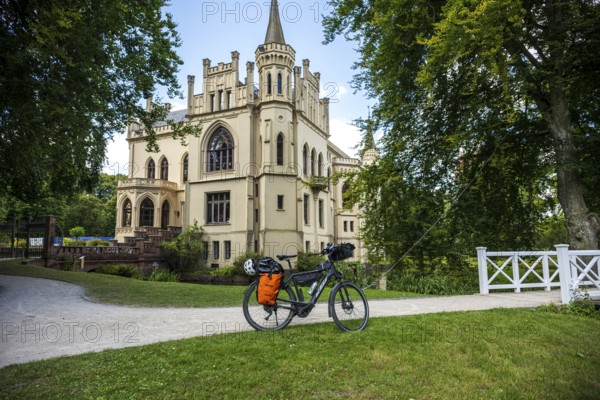 A Gothic castle with a bicycle on a path in idyllic surroundings, Evenburg Castle, Leer, East Frisia