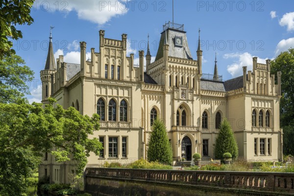 A magnificent Gothic-style castle surrounded by green trees and blossoming nature, Schloss Evenburg, Leer, East Frisia