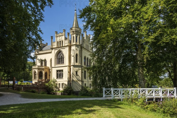 A castle in a peaceful landscape with a bridge in the foreground and a blue sky, Schloss Evenburg, Leer, East Frisia