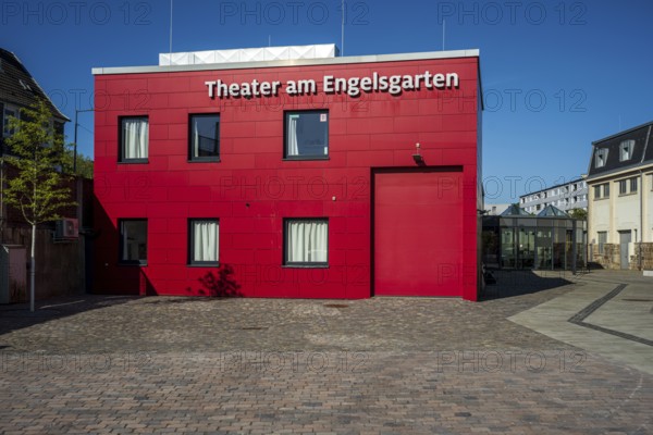 Red theatre building in front of a clear blue sky, modern style with paved forecourt, Theater am Engelsgarten in Wuppertal Barmen