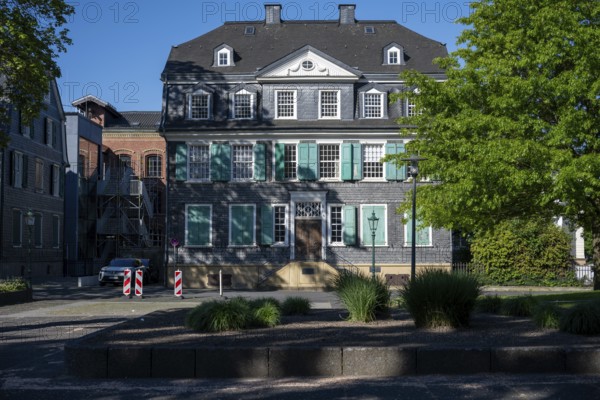 Large historic building with green shutters and surrounding trees in the sunlight, Friedrich Engels Haus in Wuppertal Barmen