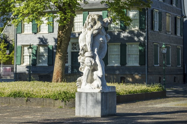 Detailed statue in front of a historic building with clear lines and soft shadows, statue The Strong Left by Alfred Hrdlicka in front of the Friedrich Engels House in Wuppertal Barmen
