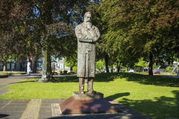 Statue of a man with crossed arms in a bright green park with trees in the background, statue of Friedrich Engels by sculptor Zeng Chenggang in the Engelsgarten Wuppertal Barmen