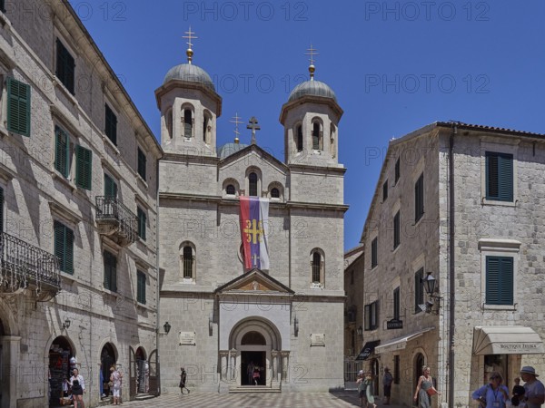 Imposing church with two towers in the historic old town, flanked by sand-coloured buildings under a blue sky Church of St. Nicholas Kotor Montenegro