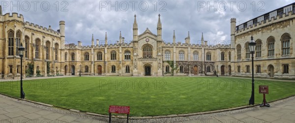 The University of Cambridge panoramic view of a historic college courtyard, featuring a grand, symmetrical facade with Gothic inspired architecture and a central clock tower