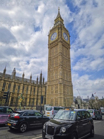 LONDON, UNITED KINGDOM - APRIL 15, 2023 A bustling London street scene featuring the iconic Elizabeth Tower, home of Big Ben. Classic black taxi cabs visible, highlighting the city traffic
