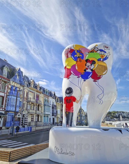 Mers-les-Bains, France - August 28, 2023 Large tooth art, Forever smile by Florence Muliardo, decorated with Disney characters. Famous Belle Epoque architecture, vibrant town villas in the background
