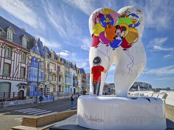 Mers-les-Bains, France - August 28, 2023 Large tooth art, Forever smile by Florence Muliardo, decorated with Disney characters. Famous Belle Epoque architecture, vibrant town villas in the background