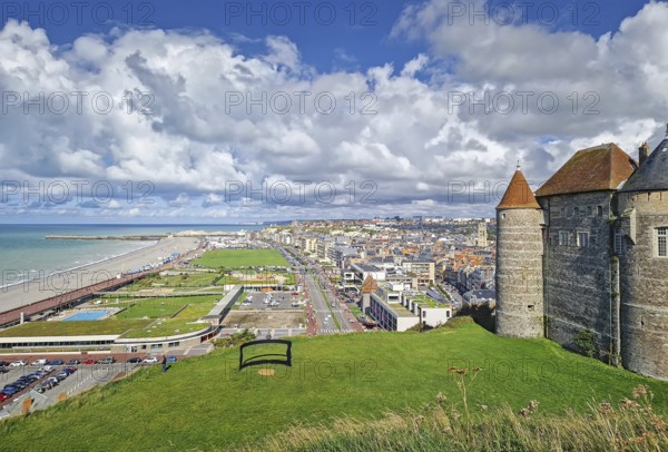 An elevated view captures Dieppe and its coastline. The historic stone castle with pointed towers overlooks the town and urban streets leading to a long pebble beach and the English Channel