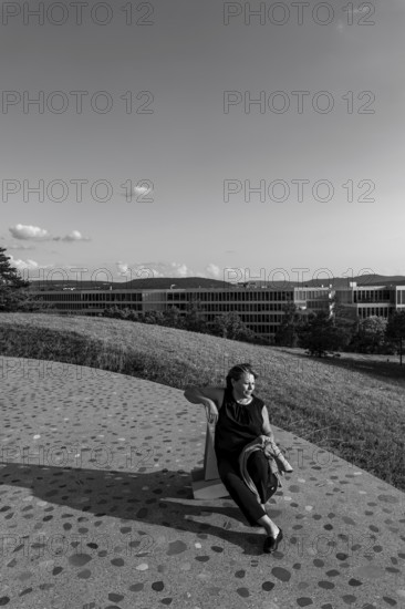 Nature Park with Panoramic View and Modern Building and a Woman Sitting on a Chair in a Sunny Summer Day in Circle, Kloten, Zurich, Zurich Canton, Switzerland