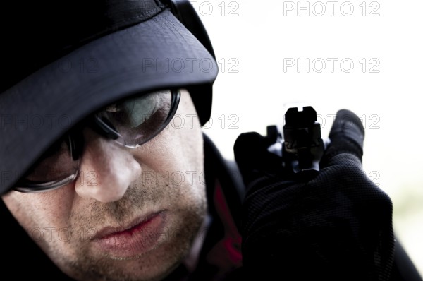 Face of a Man with Cap and Protection Eyeglasses Holding a Handgun Backward in Switzerland